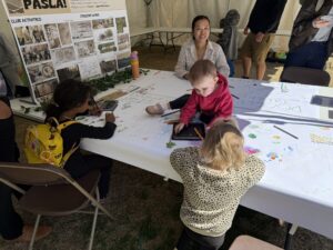 Toddlers sitting on and at PASLA's doodle table.