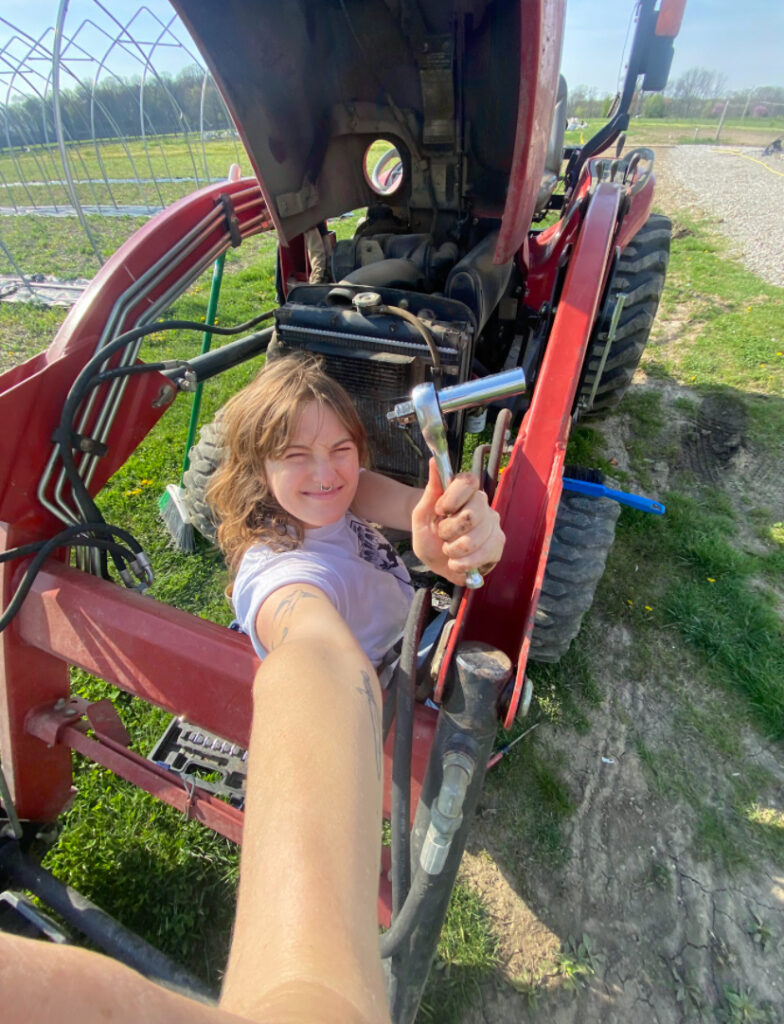 Young lady holding wrench about to work on a tractor.