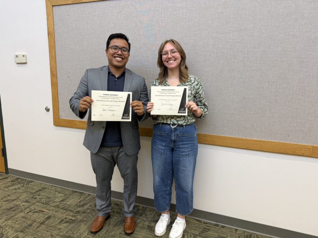 Two individuals holding certificates at a Purdue HLA research and design event.