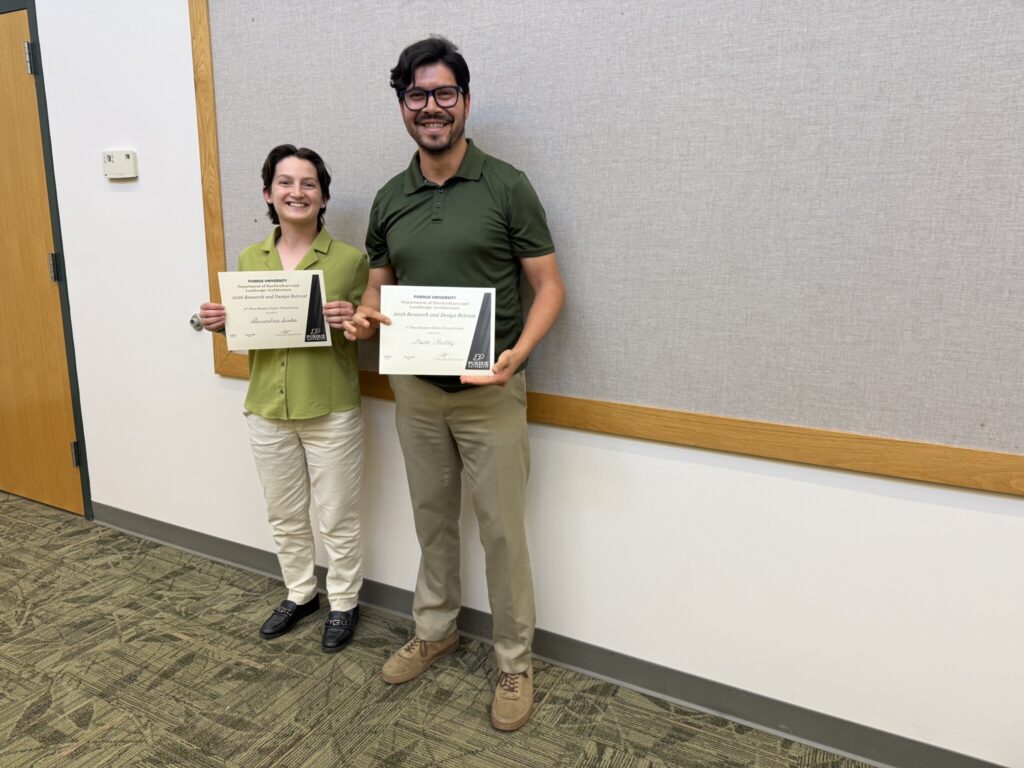Two individuals holding certificates at a Purdue HLA research and design event.