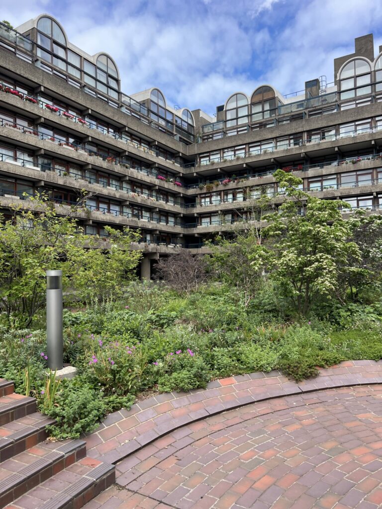 Brutalist apartment complex at London’s Barbican with tiered balconies overlooking a landscaped courtyard garden.