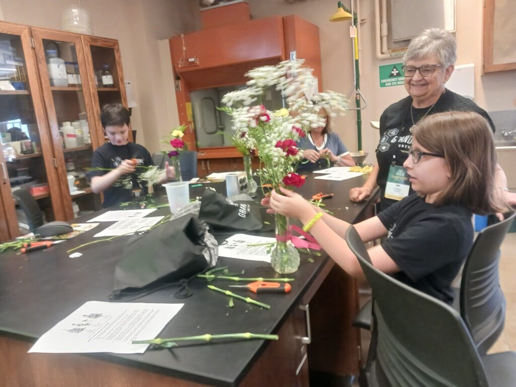 Grandparents and grandchildren create floral arrangements during a hands-on workshop.
