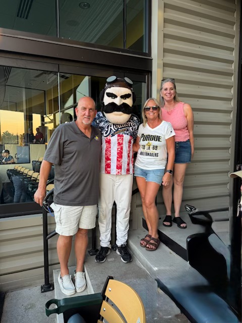 Three attendees pose with the Lafayette Aviators mascot outside a suite during the Prospect League All-Star Game.