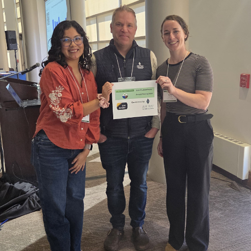 Three conference attendees hold a certificate recognizing a student poster award.