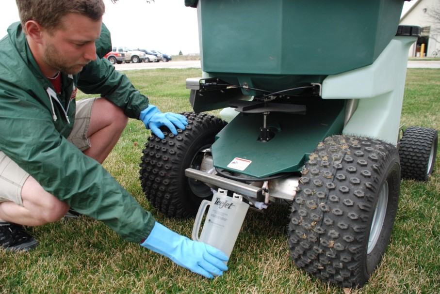 Man adjusting or working on a pesticide spreader