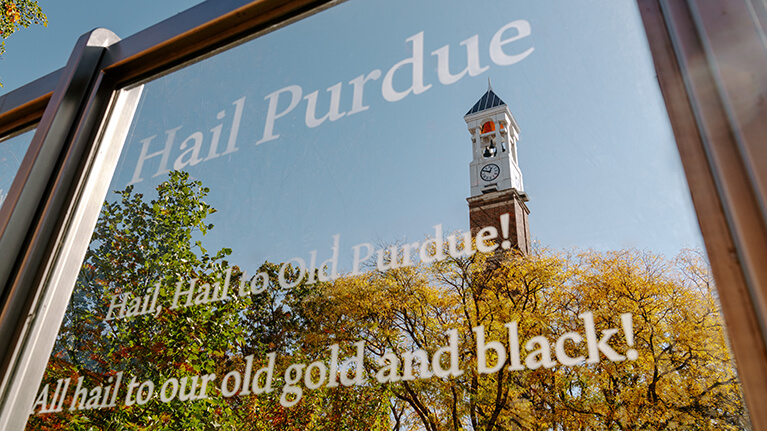 Hail Purdue on a window with the Bell Tower in the background.