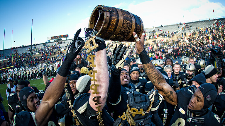 Purdue football players holding up the Oaken Bucket.