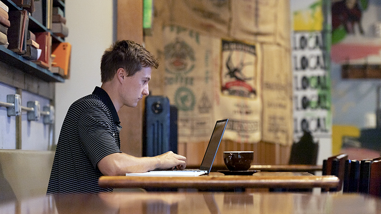 Purdue University Online student at desk on laptop.