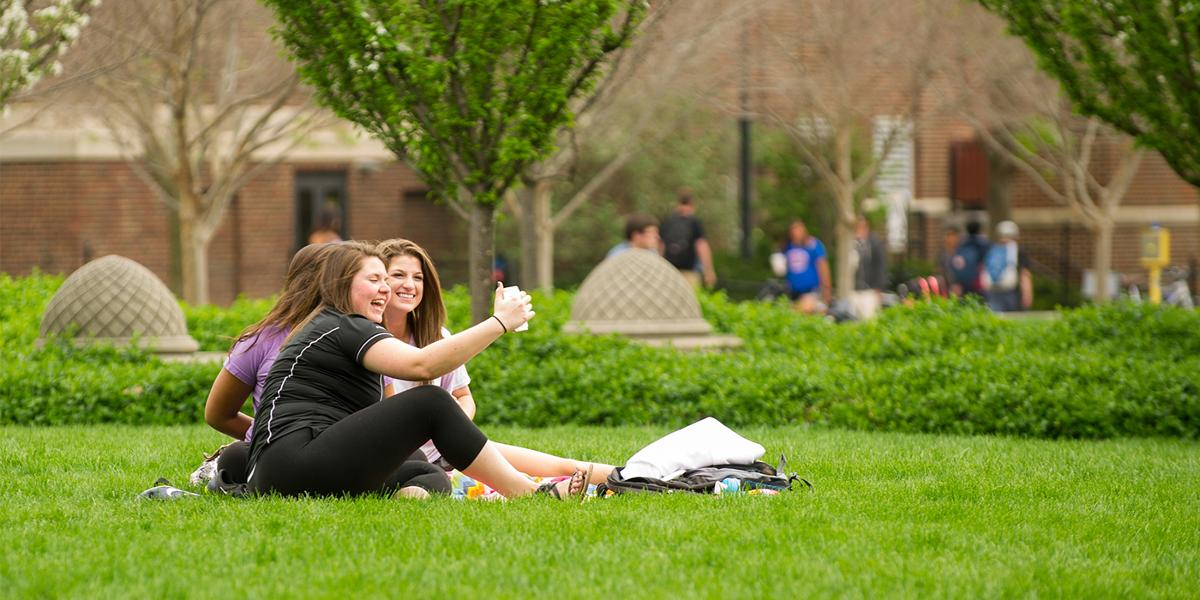 Purdue University students sitting on campus grass.