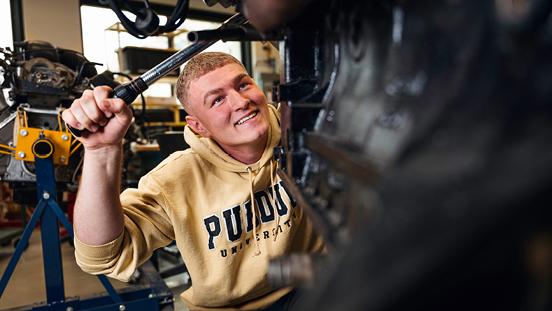 A Purdue motorsports engineering student working on a car.
