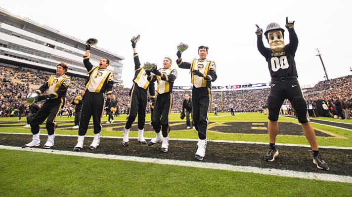 Purdue mascot and marching band members cheering in the endzone.