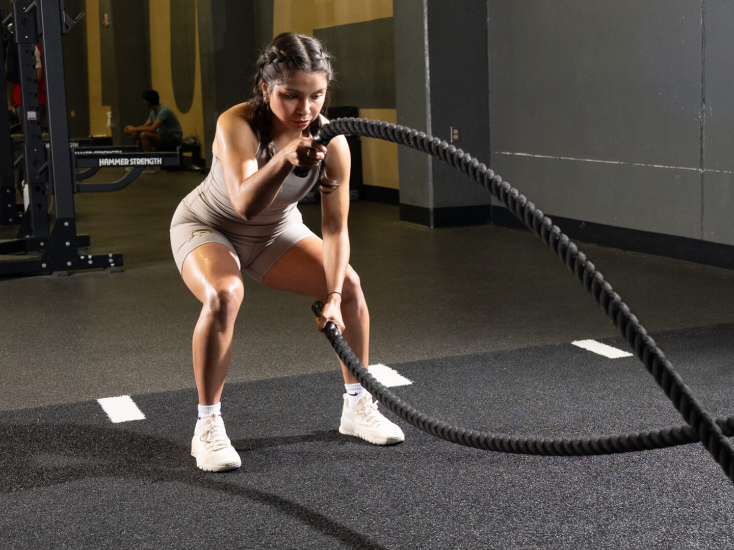 Student working out with battle ropes inside a gym facility.