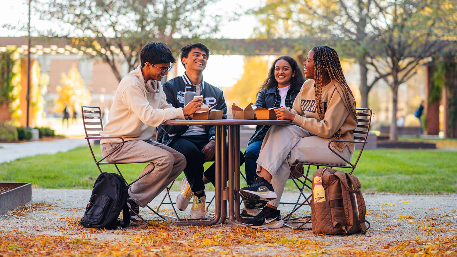 Four students eating lunch together at an outdoor table on campus.