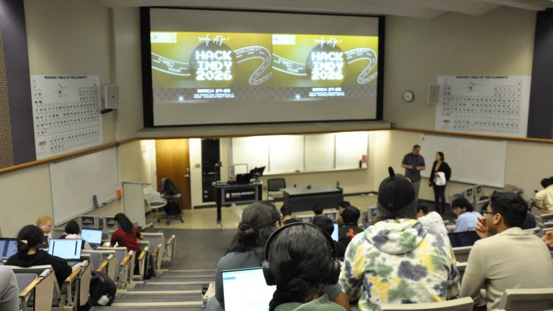 Wide view of a Purdue lecture hall filled with attendees during Hack Indy 2026, with the event title displayed on the front screen.