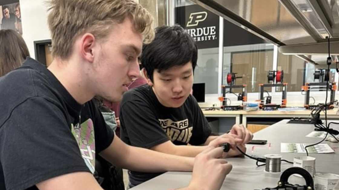 Two students at a desk in a lab, working on a project together