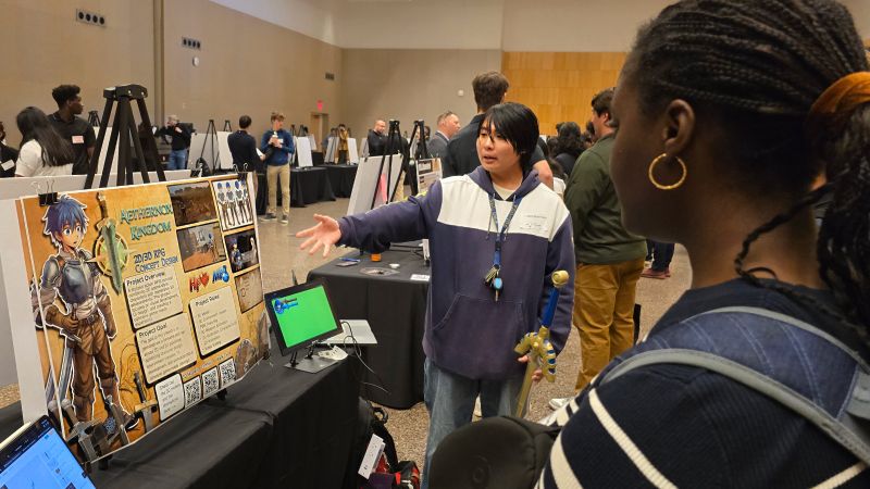 Students present a project display during a Purdue showcase in Indianapolis, with attendees viewing posters and demonstrations