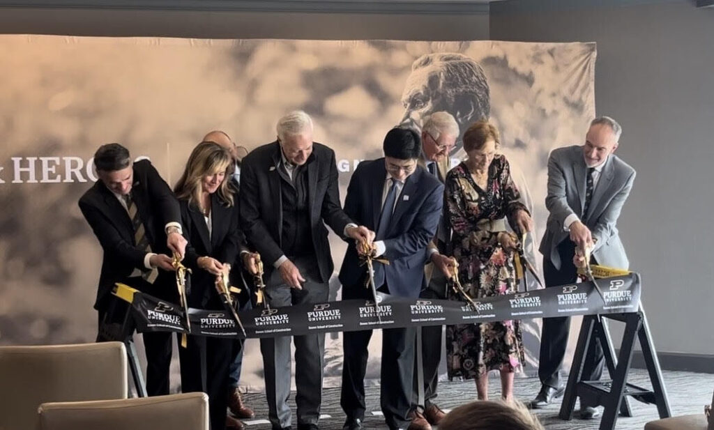 Ribbon-cutting ceremony for the Bowen School of Construction at Purdue Polytechnic in Indianapolis, with attendees cutting a Purdue‑branded ribbon