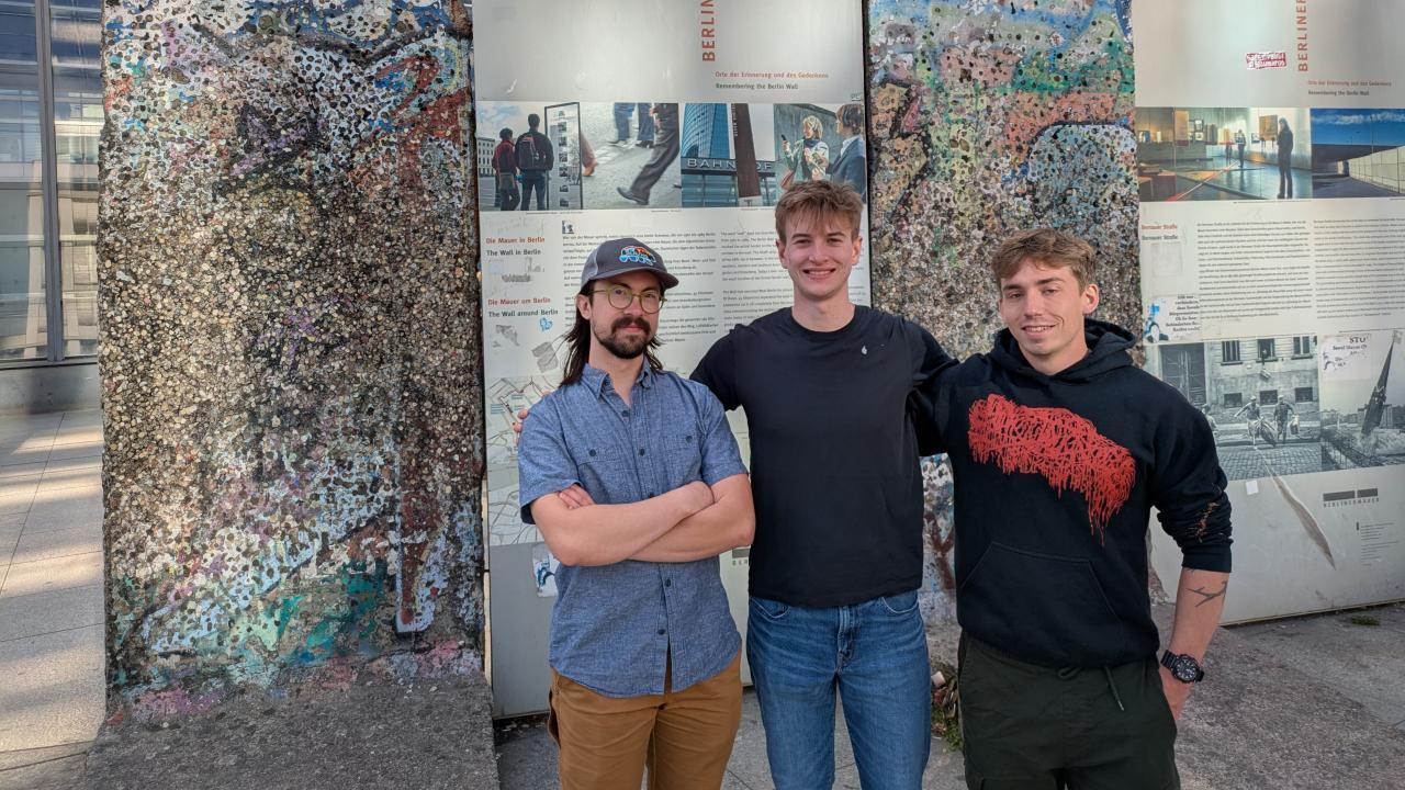 Three students stand in front of Berlin Wall fragments