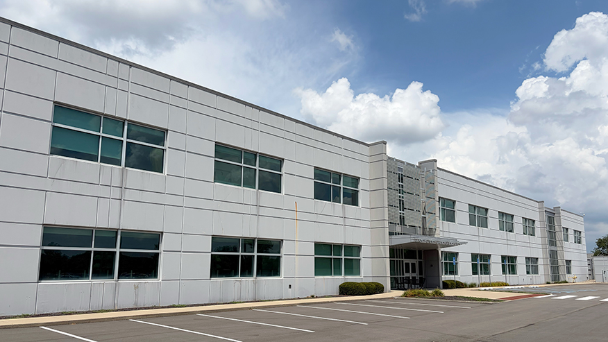 Facade of large white building with a parking lot in the front