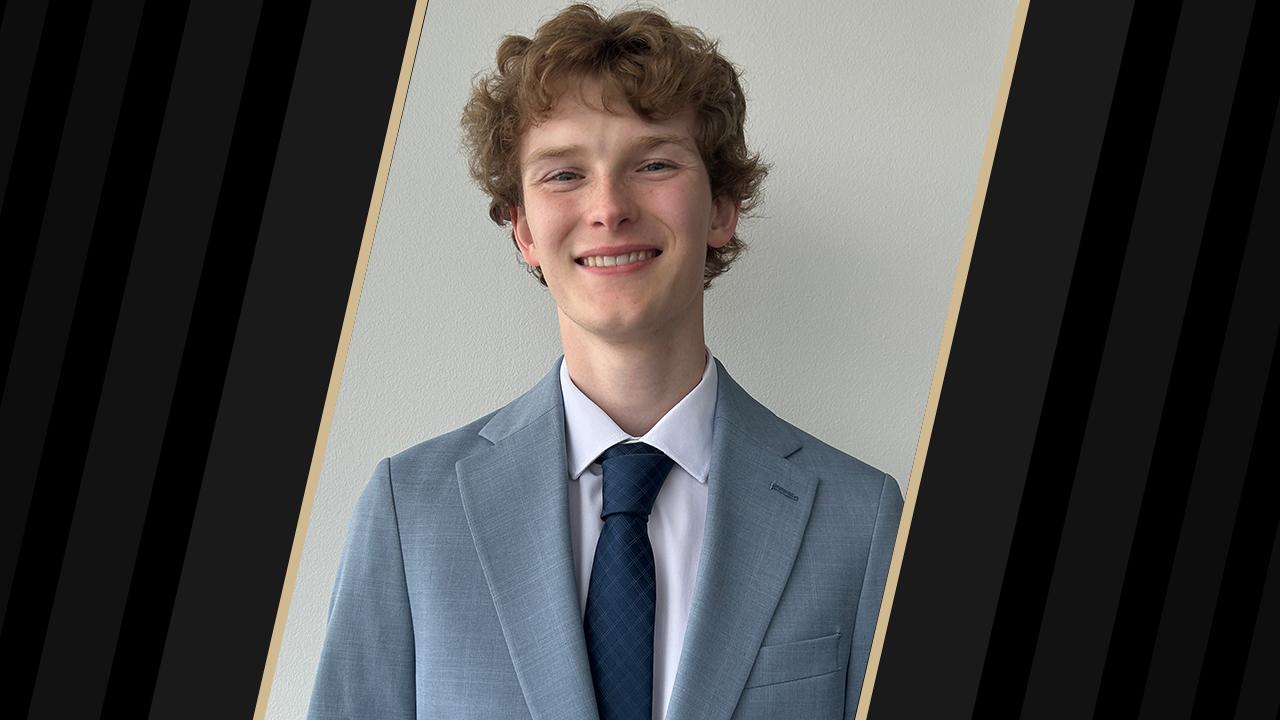 Student in a light blue suit and blue tie smiling