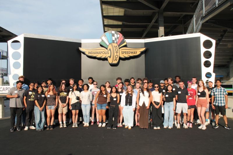 A large group of students posing in front of the Indianapolis Motor Speedway sign