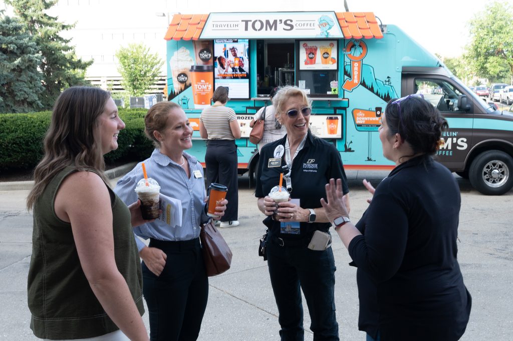 Four staff members talk outside near a coffee truck during a Purdue Indianapolis event.