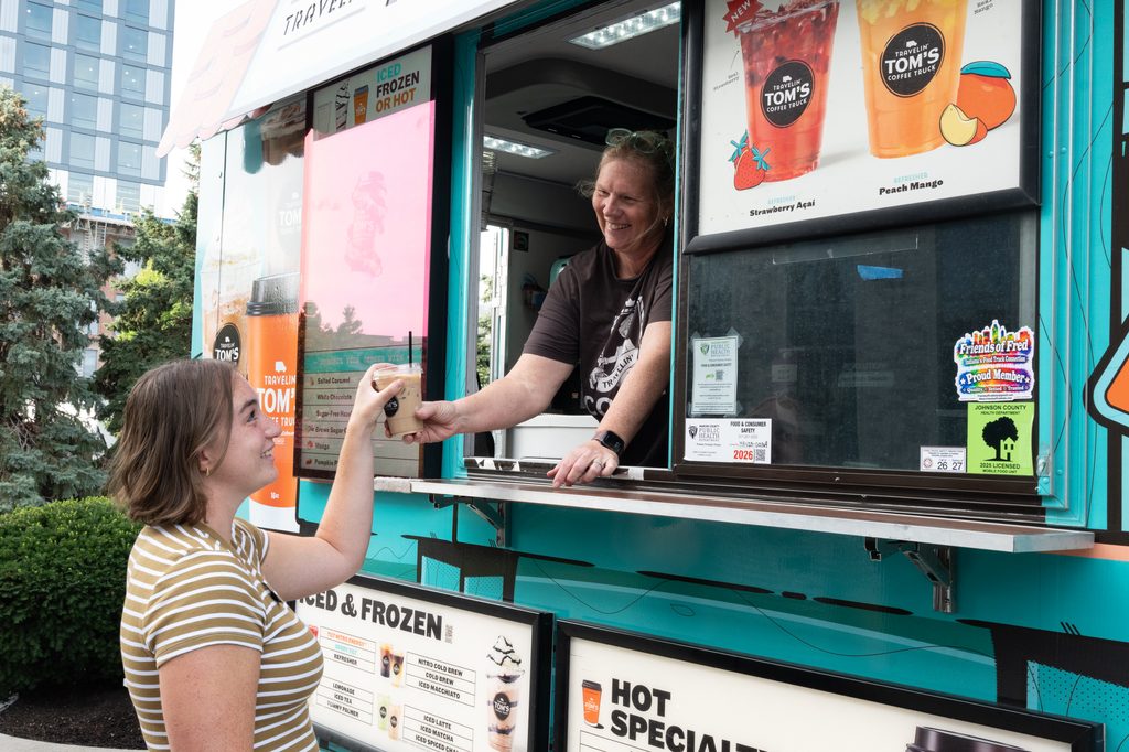 A Purdue staff member receives an iced coffee from a woman inside a food truck during a Purdue Indianapolis event.