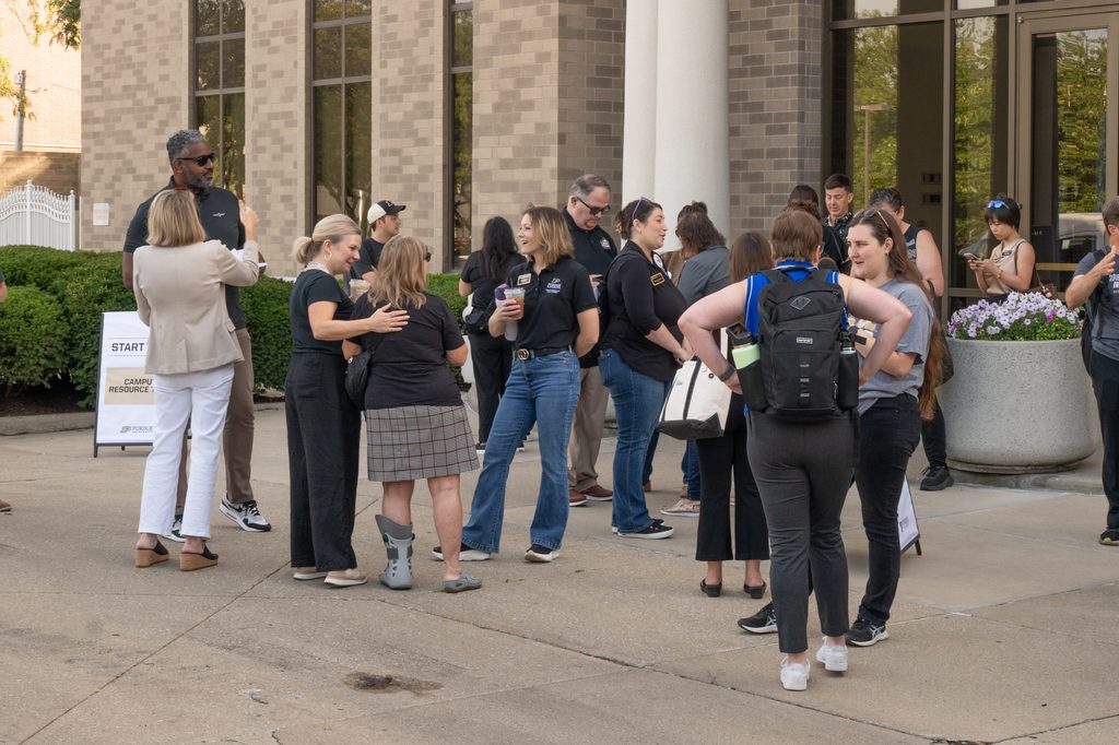 Event attendees gather outside the Sigma Theta Tau building, standing and talking in small groups.