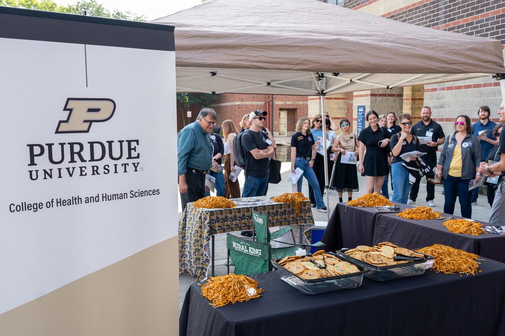Tour participants gather beside a College of Health and Human Sciences welcome table.