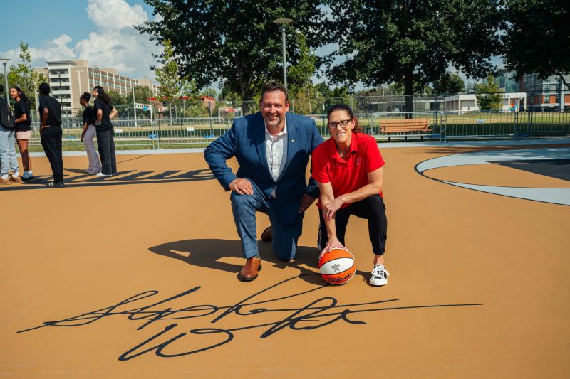 Senior Vice Provost of Purdue University for Indianapolis posing at a basketball court with Indiana Fever trailblazer