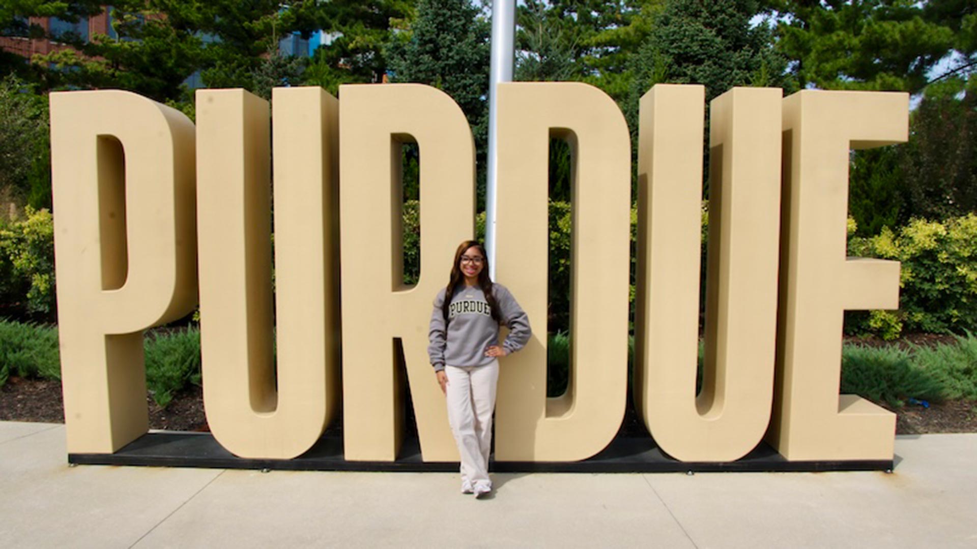 Harmony Oliver stands in front of a large Purdue side outside at the Purdue in Indianapolis location.