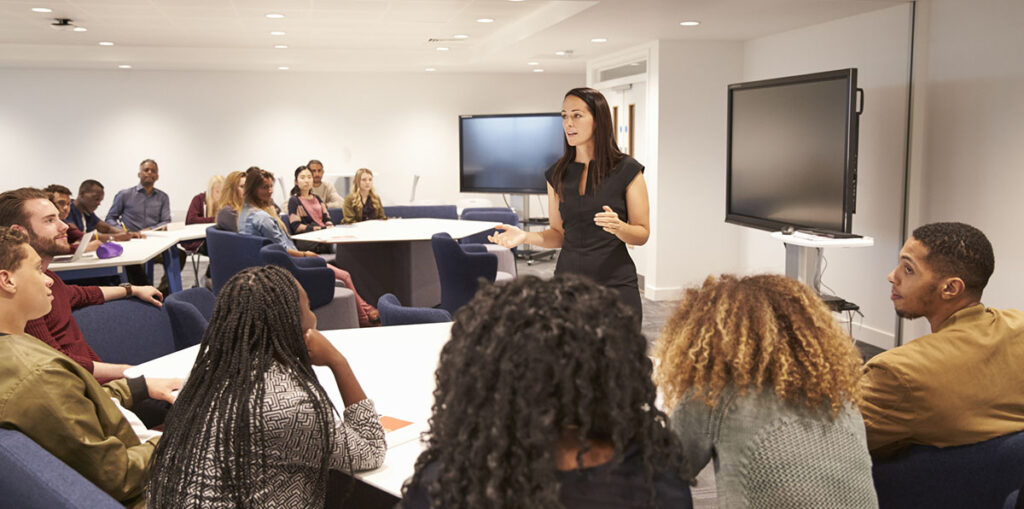 Female teacher addressing university students in a classroom