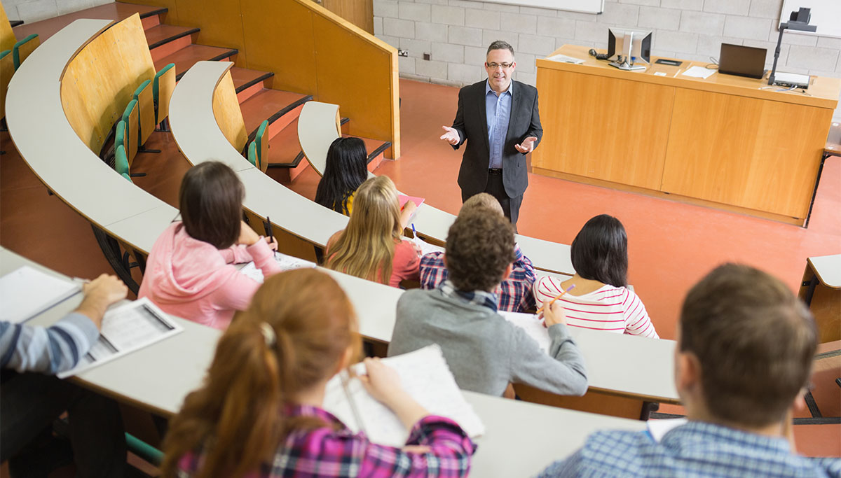 Elegant teacher with students sitting at the college lecture hall