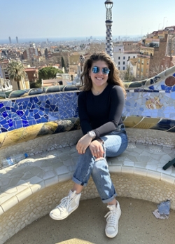Talia Hirsch sits on a bench with colorful mosaic tiles in Park Guell in Barcelona
