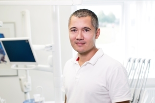 Doctor wearing white polo shirt trained in Lean Six Sigma for healthcare standing in hospital room