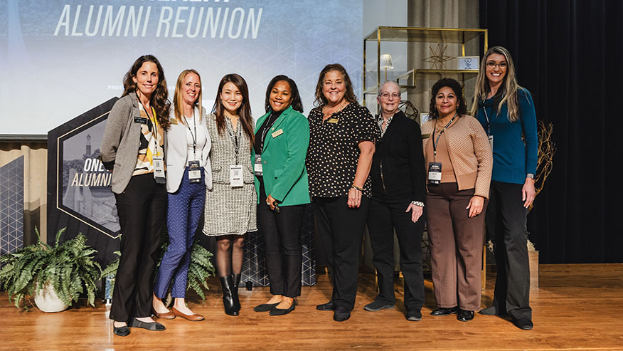 A group of eight women standing together on a stage