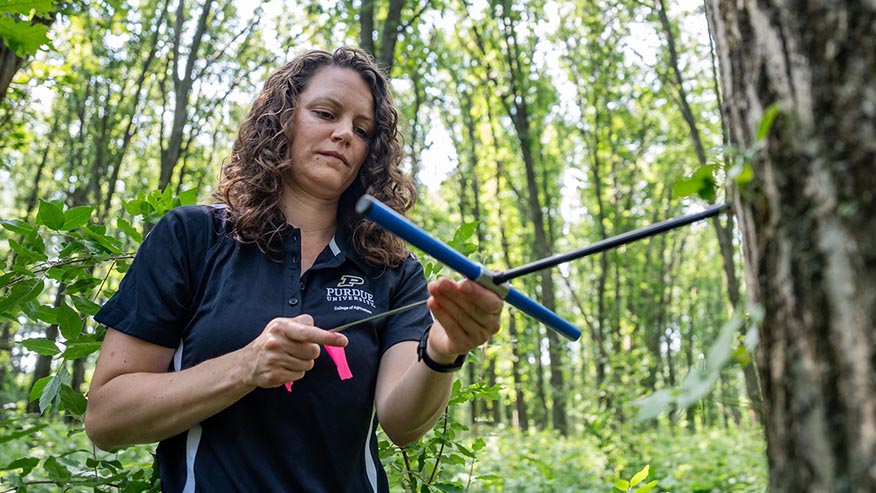 Woman holding tool of some sort in a forest
