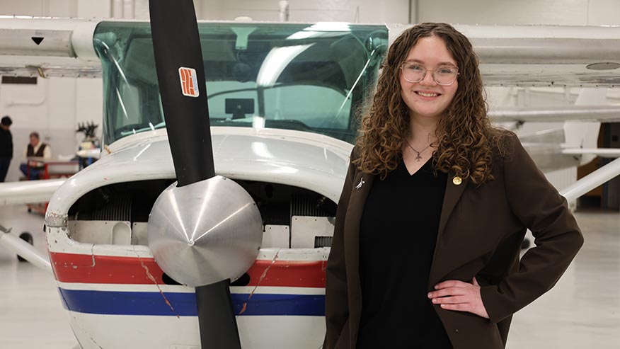 Purdue student standing in front of airplane in hangar