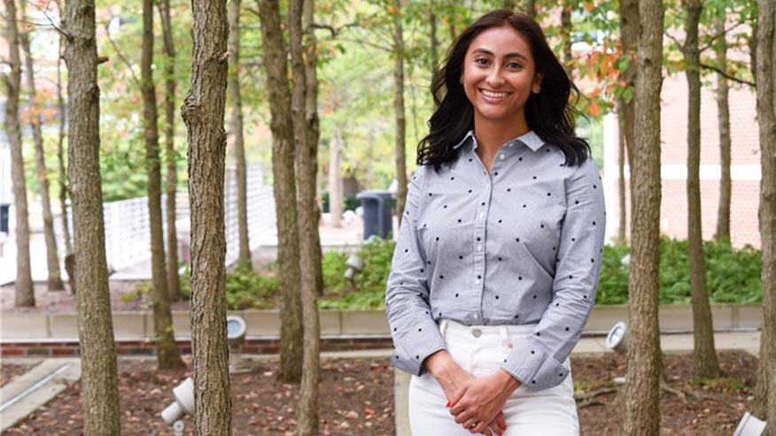 Purdue student smiling and standing in front of trees
