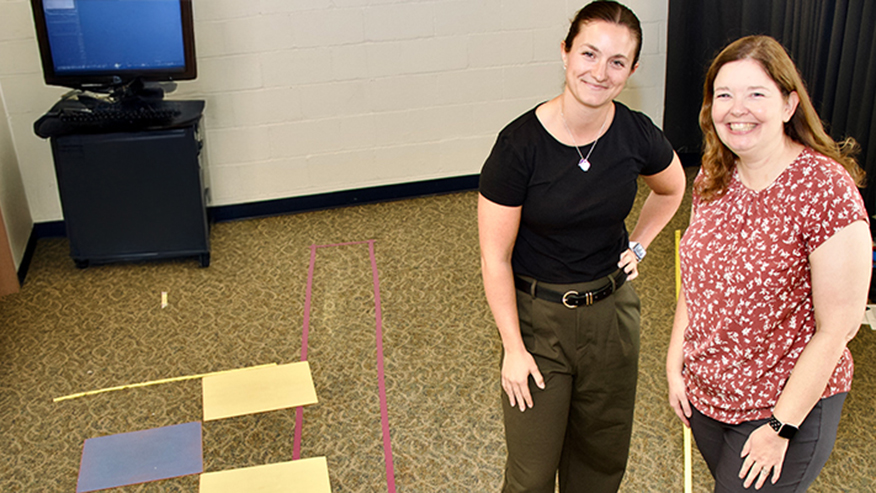 Two women in room with tape and lines on floor