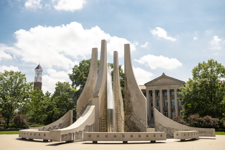Purdue’s Class of 1939 Water Sculpture with Hovde Hall and the Purdue Bell Tower in the background on a sunny day.