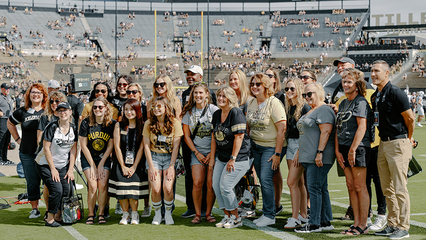 Local educators stand on a football field while being honored by the crowd.