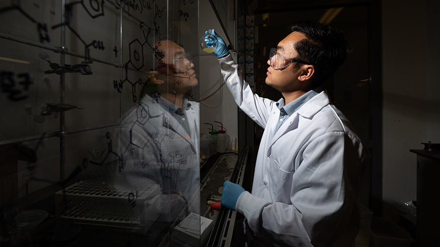 Man writes on clear board in lab