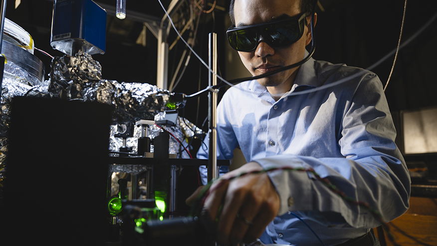 Physicist Tongcang Li, wearing dark safety glasses, uses magnetic resonance spectroscopy equipment in his lab on the Purdue University campus.