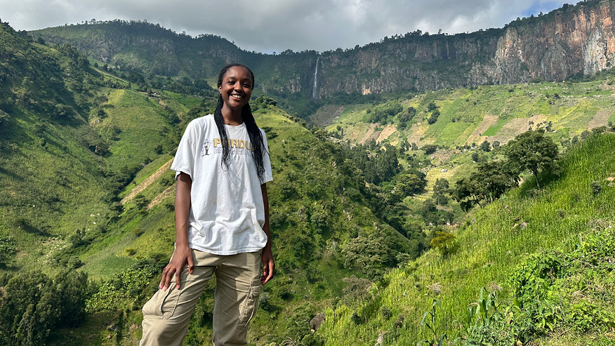 Student standing in front of mountainous area