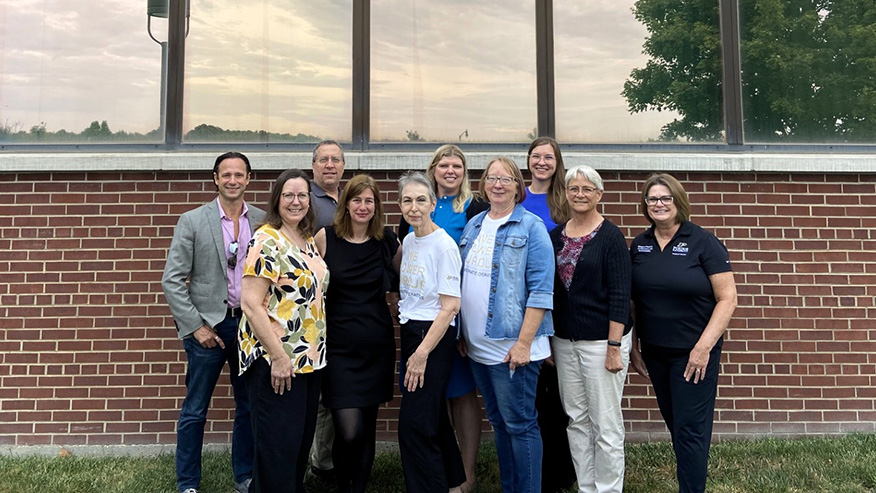 Campus Planning and Architecture department, a group of 10 Purdue faculty and staff, stand together outside a brick building, smiling at the camera.