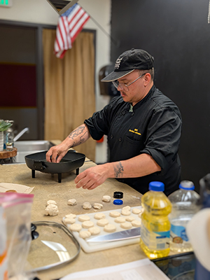 Purdue Global student Westley Penland cooking food for campers.