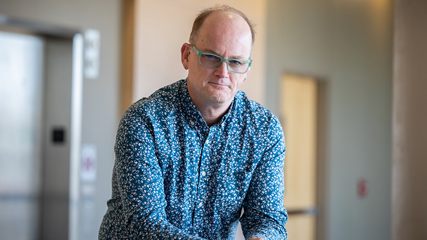 Purdue University researcher John Tesmer, wearing glasses, stands in a lobby