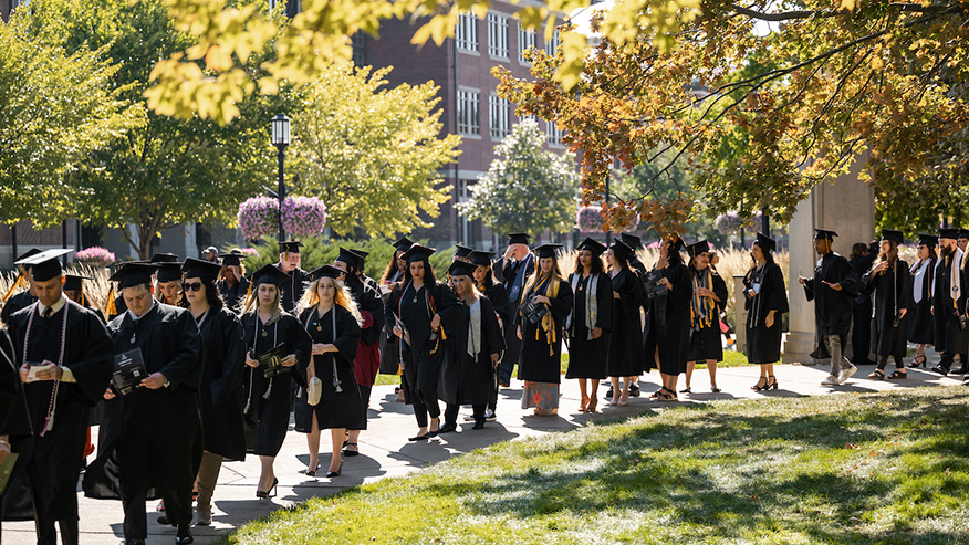 Purdue Global graduates walking across campus in the fall.