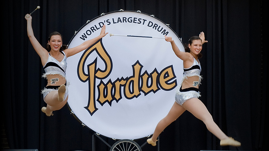 Dancers jumping in front of large drum